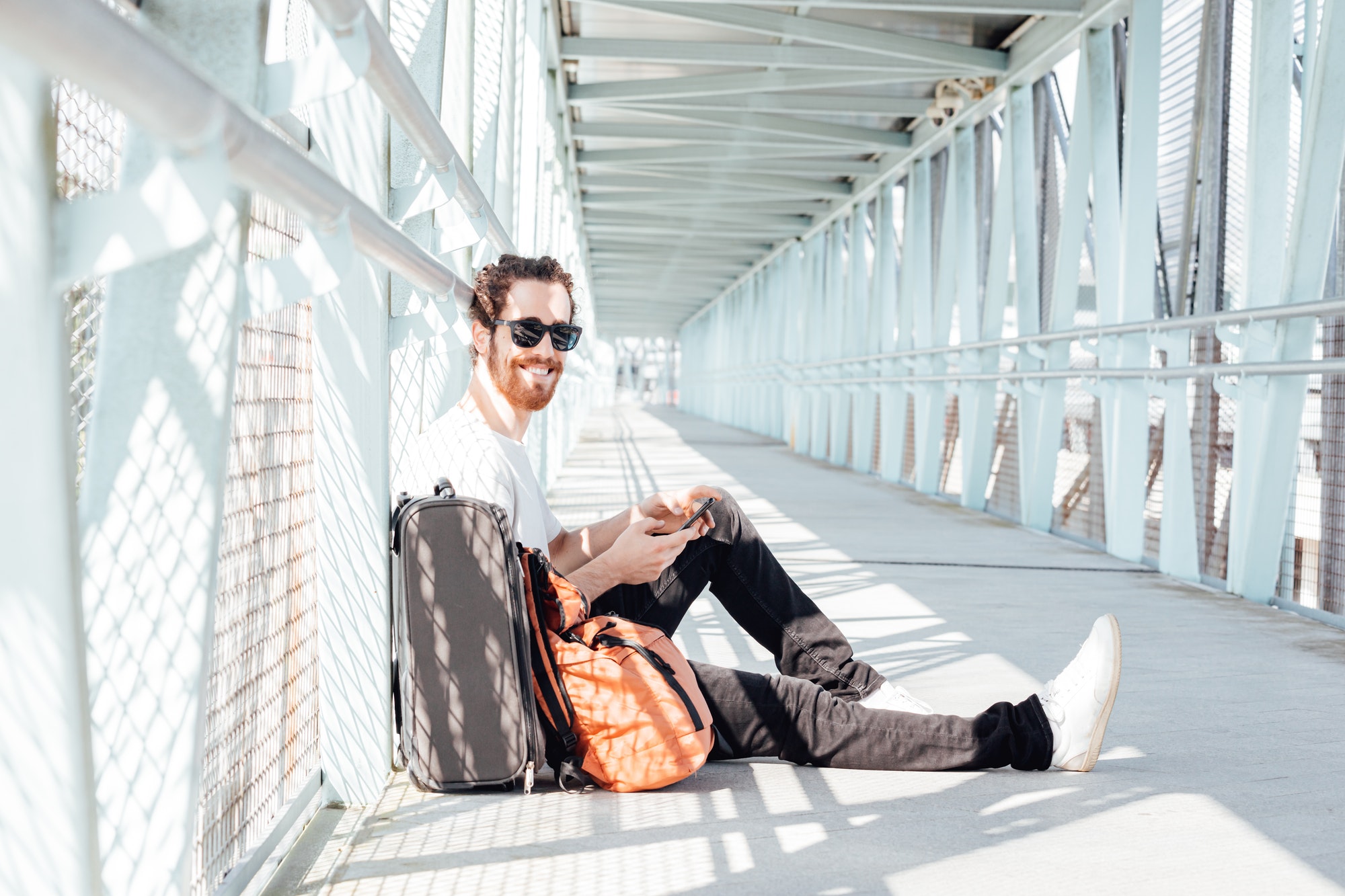 Urban young man talking on smart phone traveling inside in airport. Casual young businessman