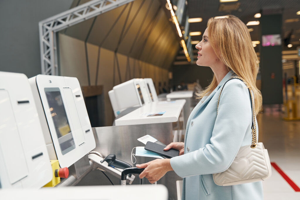 Cestujúci so samoobslužným check-in automatom v modernej odletovej hale letiska