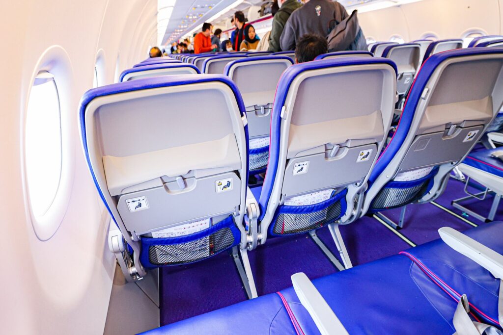 Interiér kabíny lietadla Wizz Air s modrými sedadlami a cestujúcimi pri nástupe